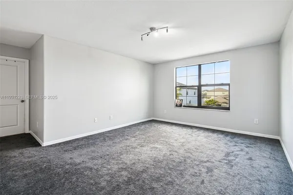 an empty room with windows and ceiling fan
