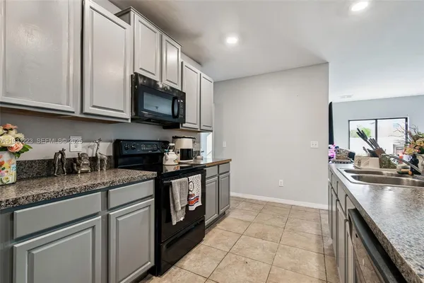 a kitchen with granite countertop a sink a stove and cabinets