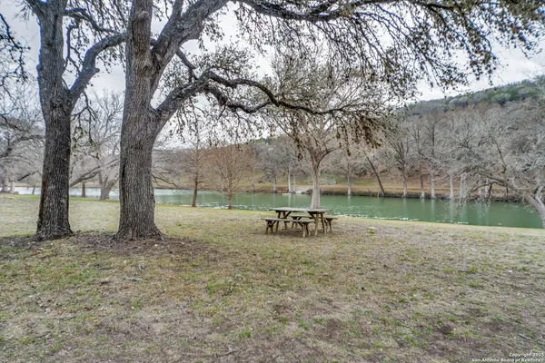 a view of a lake with table and chairs under an umbrella