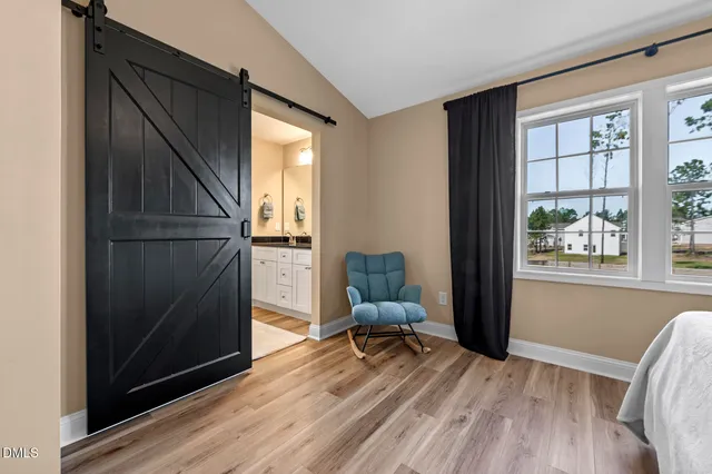 a bedroom with a bed and a large window with wooden floor