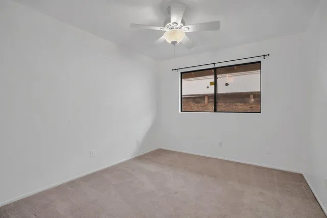 an empty room with a window and a ceiling fan