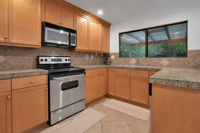a kitchen with stainless steel appliances granite countertop a stove a sink and a microwave