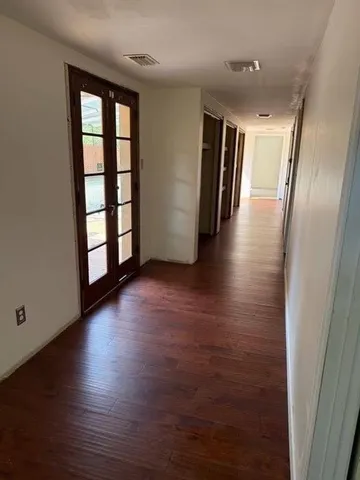 an empty room with wooden floor and windows