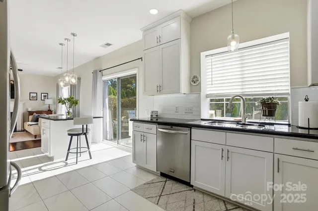 a kitchen with stainless steel appliances kitchen island granite countertop a refrigerator a stove a microwave oven a dining table and chairs with wooden floor