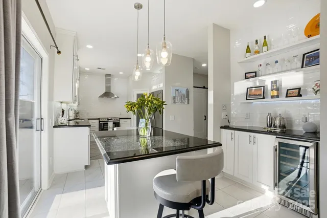 a kitchen with stainless steel appliances granite countertop a sink a stove a refrigerator and chairs