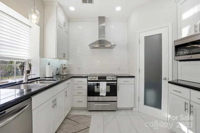 a kitchen with stainless steel appliances kitchen island granite countertop a refrigerator and a sink