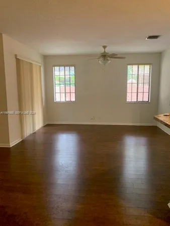 a view of empty room with wooden floor and fan