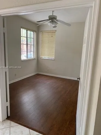an empty room with wooden floor fan and windows
