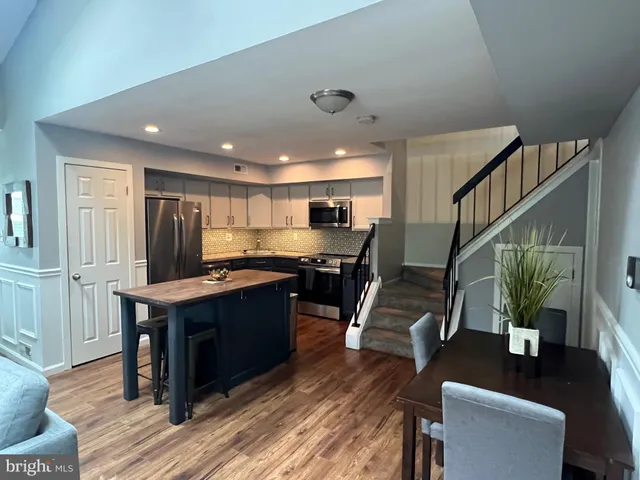 a kitchen with stainless steel appliances kitchen island granite countertop a table chairs and a refrigerator