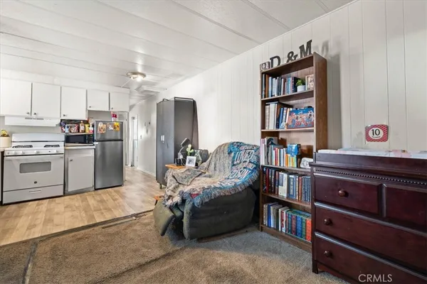 a living room with stainless steel appliances furniture a rug and a kitchen view