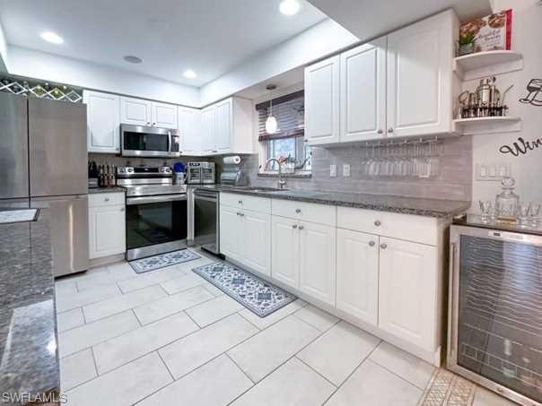 3790 35th Avenue Northeast Naples, FL 34120 - Photo 18 of 27 a kitchen with stainless steel appliances granite countertop a stove top oven a sink and a refrigerator