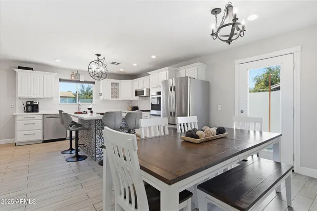 a kitchen with stainless steel appliances kitchen island granite countertop a table chairs and a refrigerator