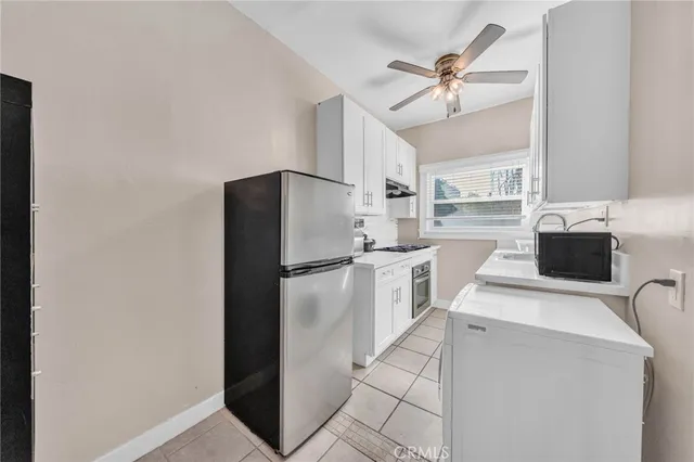 a kitchen with a refrigerator a stove top oven a cabinetry and a chandelier