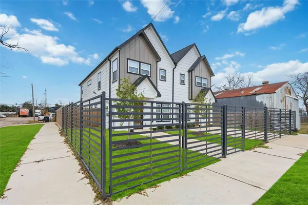 a view of a house with wooden fence next to a yard