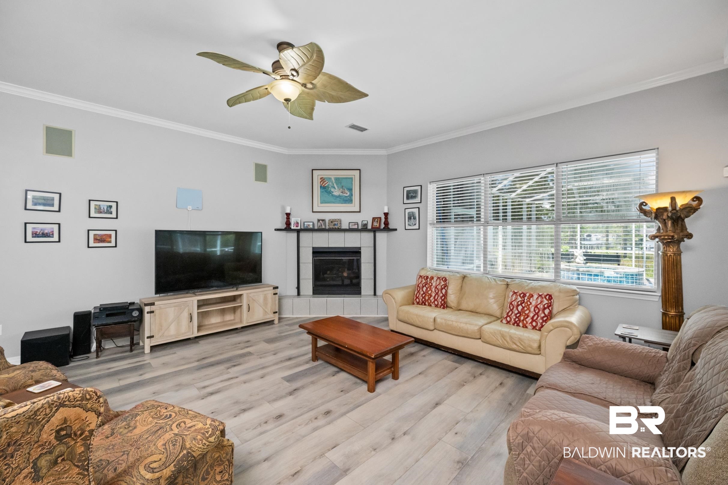 8585 Bay Harbor Road Elberta, AL 36530 - Photo 13 of 51 Living room with light wood-type flooring, ornamental molding, ceiling fan, and a tile fireplace