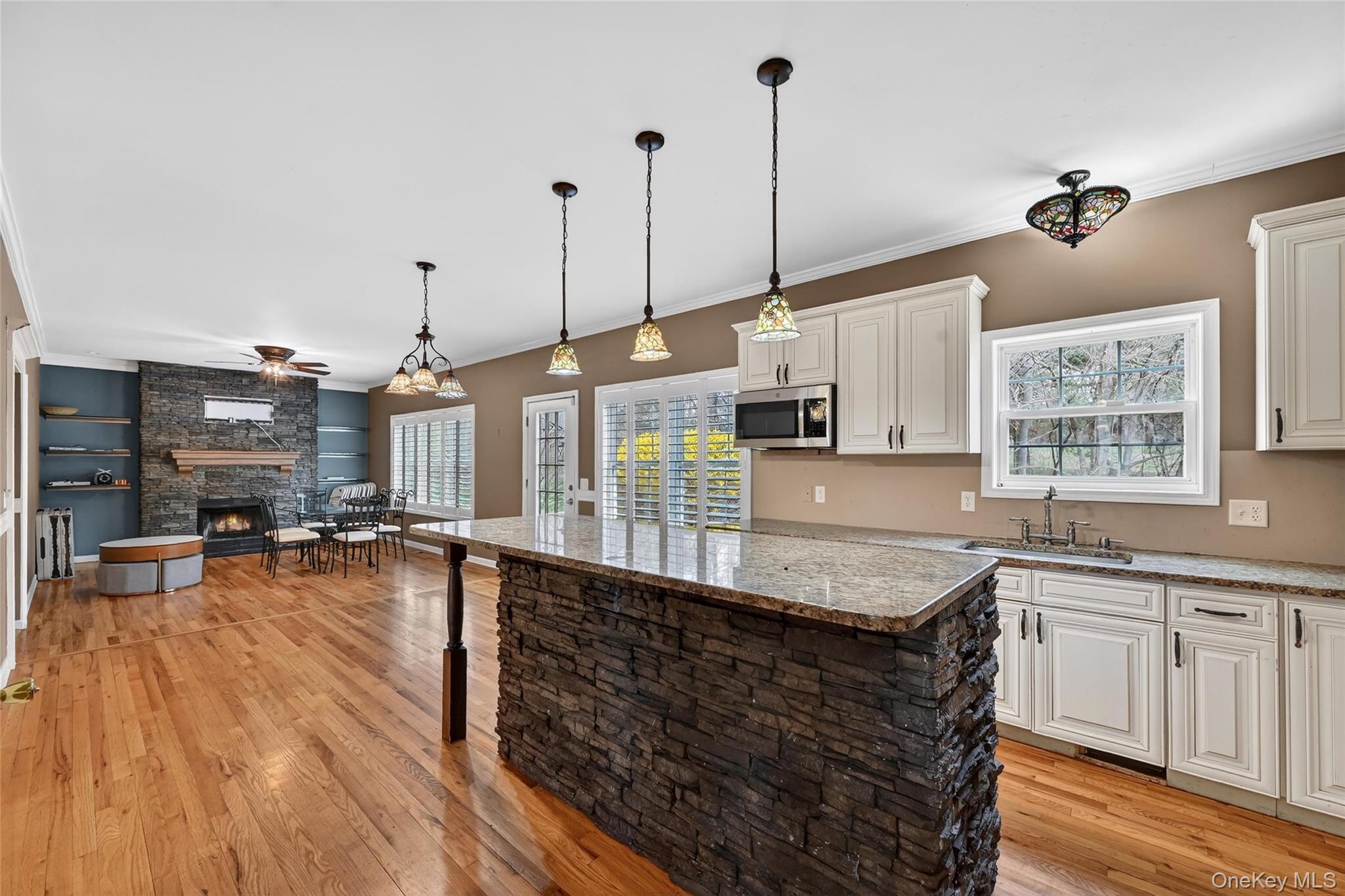 1071 Craigville Road Chester, NY 10918 - Photo 15 of 48 Kitchen with light stone counters, a center island, white cabinets, light wood-style floors, and ornamental molding