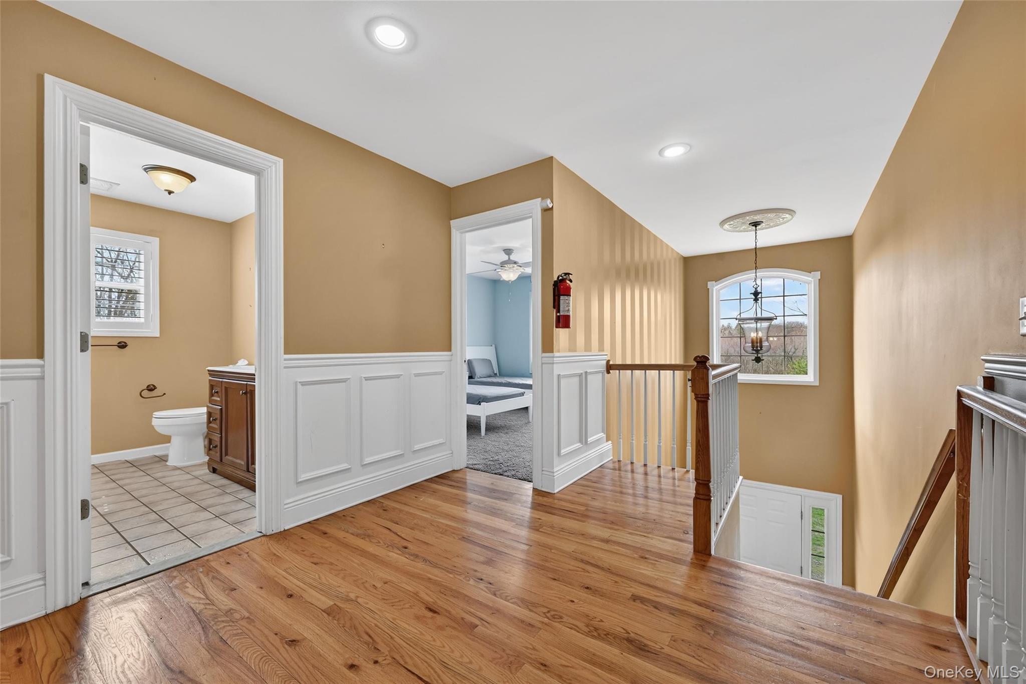1071 Craigville Road Chester, NY 10918 - Photo 21 of 48 Hallway with light wood-style flooring, an upstairs landing, plenty of natural light, hanging lights, and wainscoting