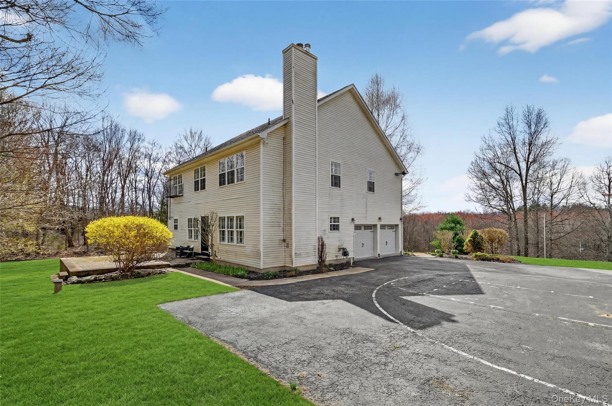 1071 Craigville Road Chester, NY 10918 - Photo 43 of 48 View of property exterior featuring a chimney, an attached garage, a lawn, and driveway