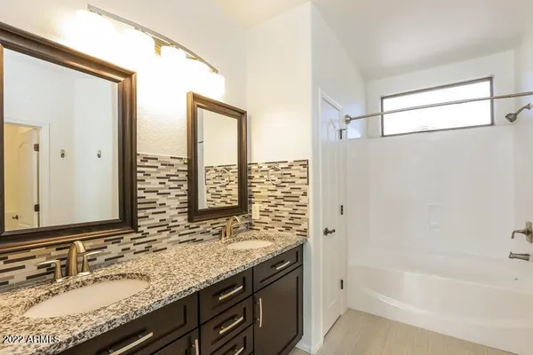 a bathroom with a granite countertop sink mirror and a bathtub