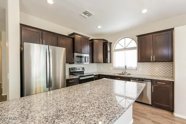 a kitchen with granite countertop stainless steel appliances a sink cabinets and a counter top space