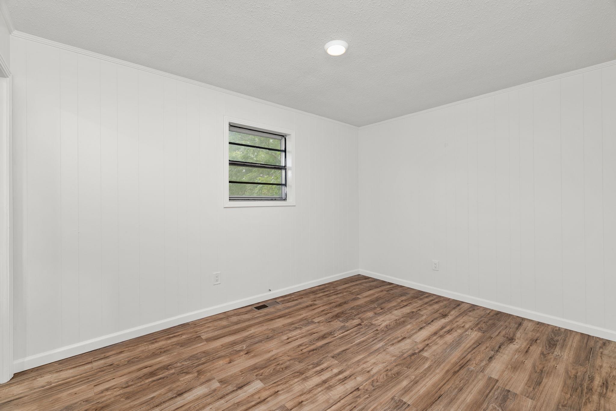 217 Red Bay Road Golden, MS 38847 - Photo 12 of 33 Spacious room featuring wood-finish flooring, white paneling, a recessed ceiling light, and a window with security bars