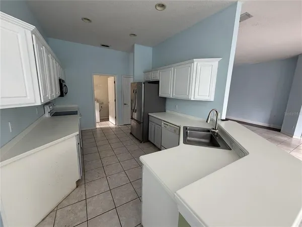 a kitchen with stainless steel appliances a sink a stove and white cabinets