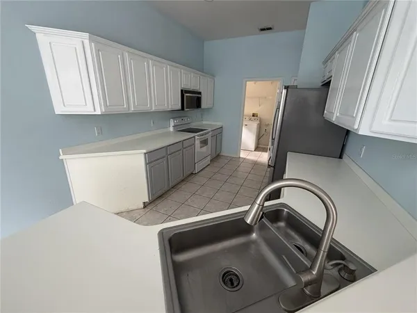 a kitchen with a sink a refrigerator and cabinets