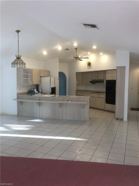 538 Roma Court Naples, FL 34110 - Photo 16 of 19 a large kitchen with kitchen island a sink stainless steel appliances and a chandelier