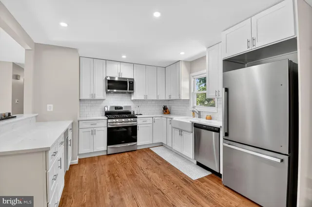 a kitchen with a refrigerator a stove top oven a sink and dishwasher with wooden floor