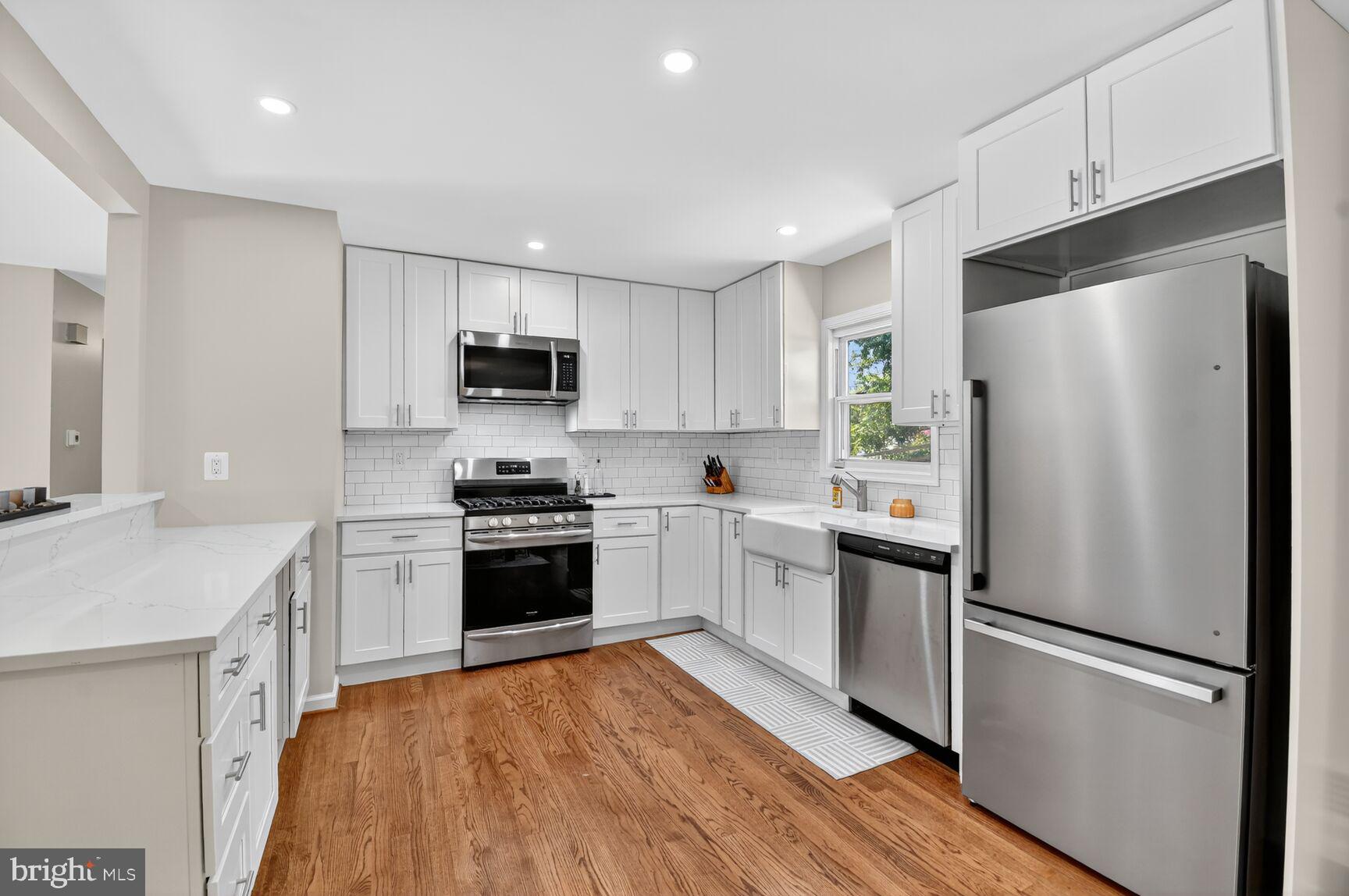 6801 Trowbridge Place Fort Washington, MD 20744 - Photo 7 of 30 a kitchen with a refrigerator a stove top oven a sink and dishwasher with wooden floor