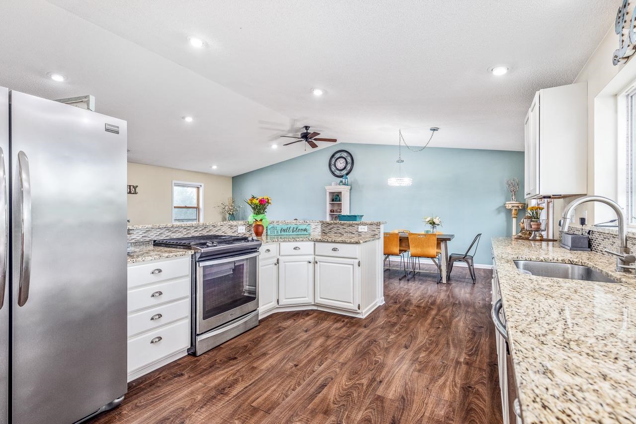10388 Telegraph Road Winnebago, IL 61088 - Photo 12 of 48 a large kitchen with stainless steel appliances kitchen island granite countertop a large stove a sink a refrigerator and white cabinets with wooden floor