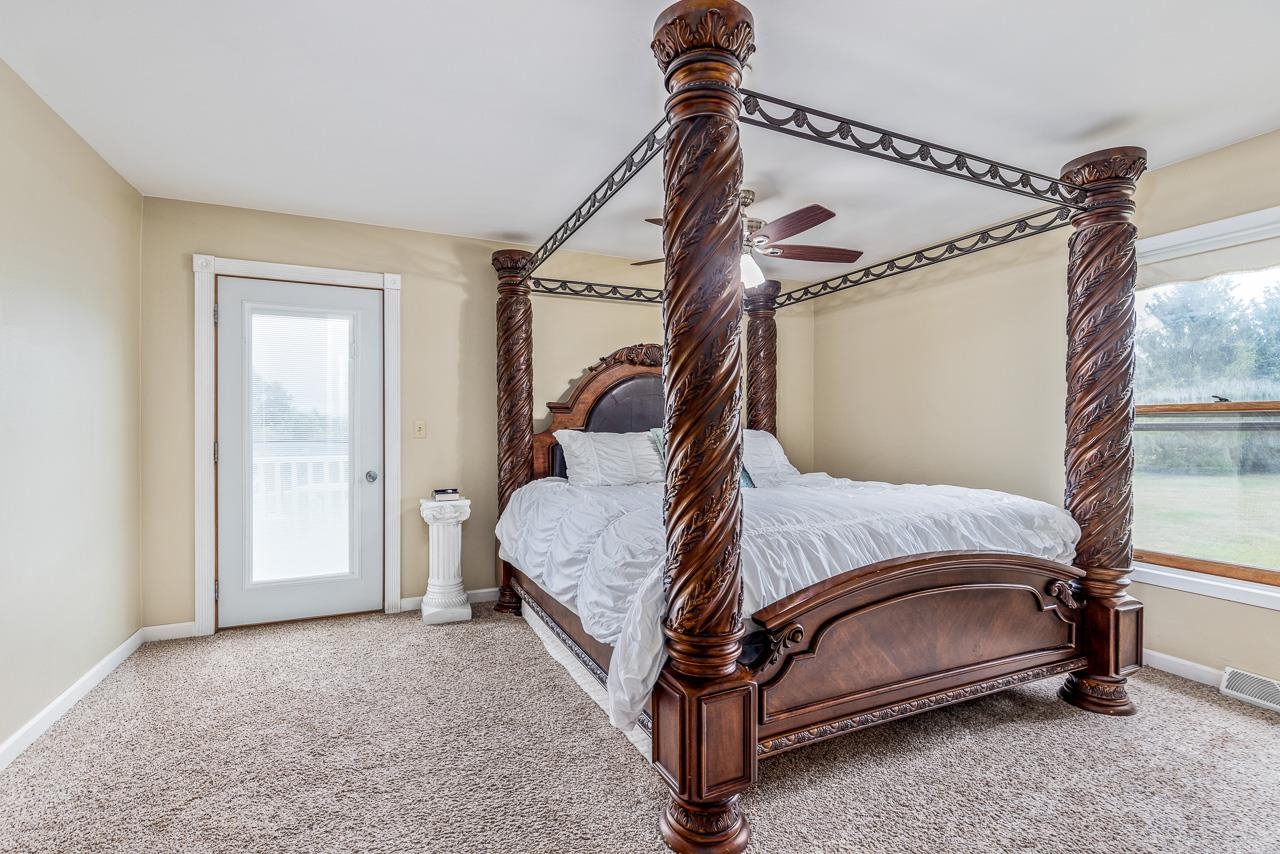10388 Telegraph Road Winnebago, IL 61088 - Photo 16 of 48 a bed sitting in a bedroom next to a window and a wooden floor