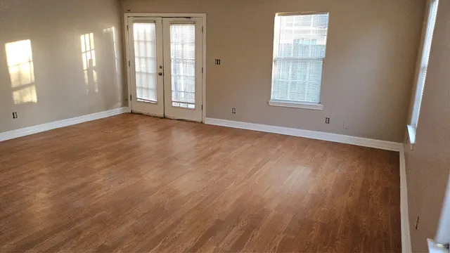 an empty room with wooden floor and windows