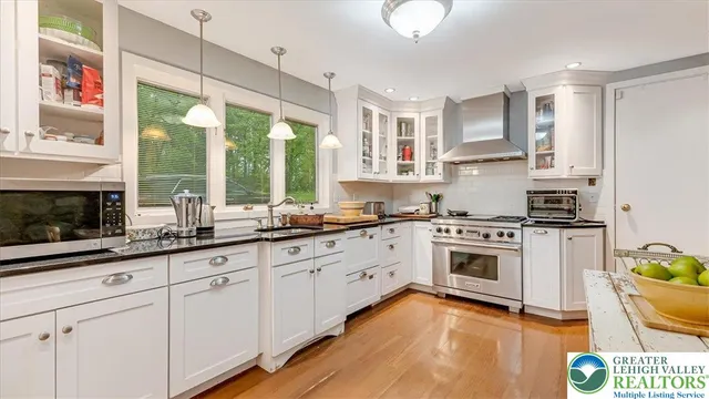 a kitchen with stainless steel appliances granite countertop a stove a refrigerator a sink a dining table and chairs