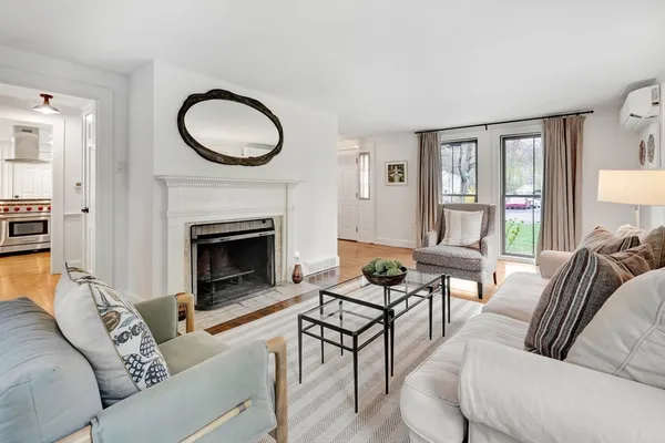 a living room with furniture a rug a fireplace and a large window