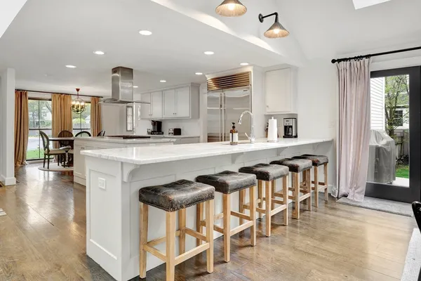 a kitchen with stainless steel appliances kitchen island granite countertop a table chairs sink and cabinets