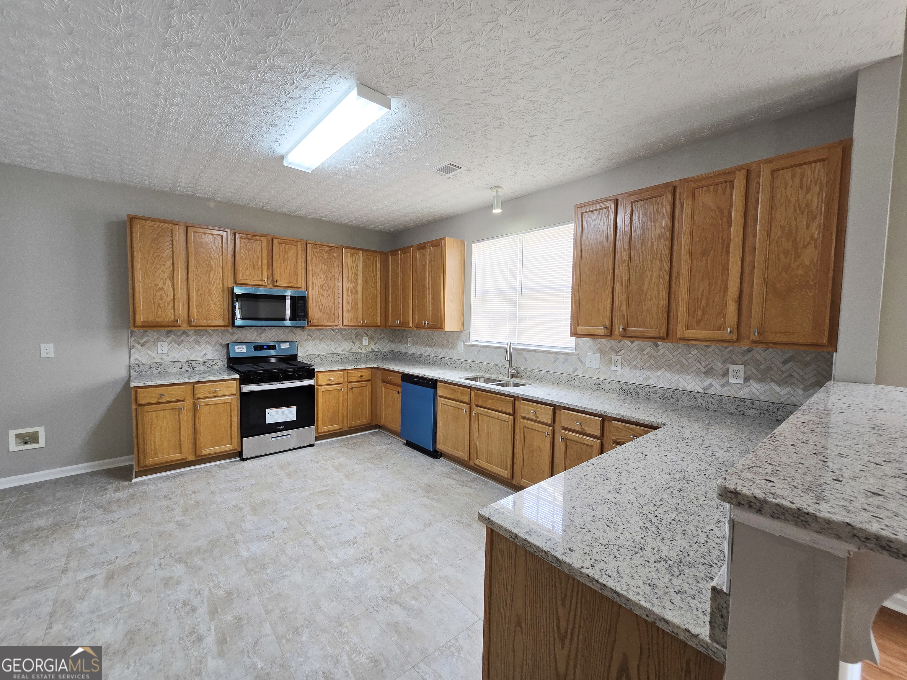 537 Goldfinch Way Stockbridge, GA 30281 - Photo 5 of 20 a kitchen with stainless steel appliances granite countertop wooden cabinets a stove top oven a sink and dishwasher