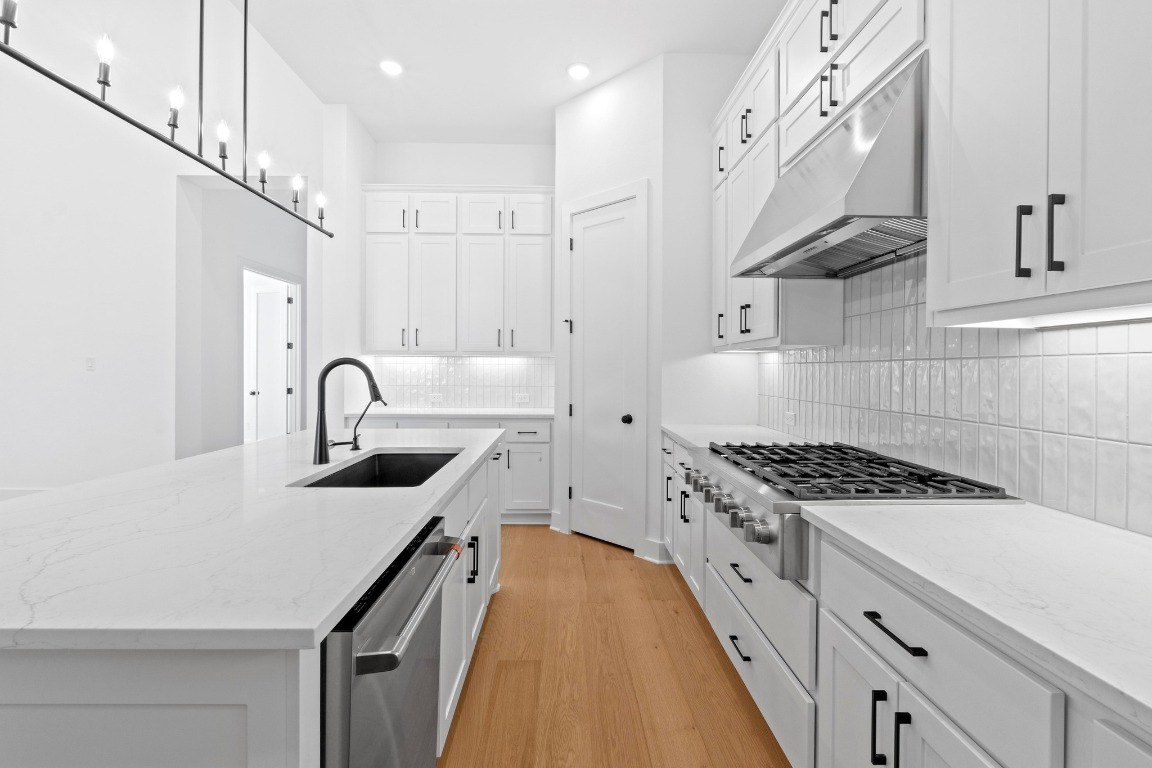 3209 Moon Ridge Road Georgetown, TX 78628 - Photo 7 of 28 a kitchen with stainless steel appliances granite countertop a sink a stove and a wooden floors