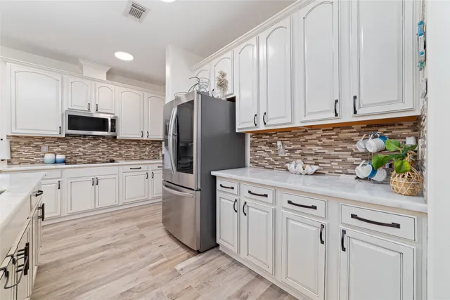 a kitchen with white cabinets and stainless steel appliances