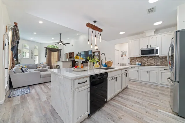 a kitchen with kitchen island granite countertop a sink counter top space and stainless steel appliances