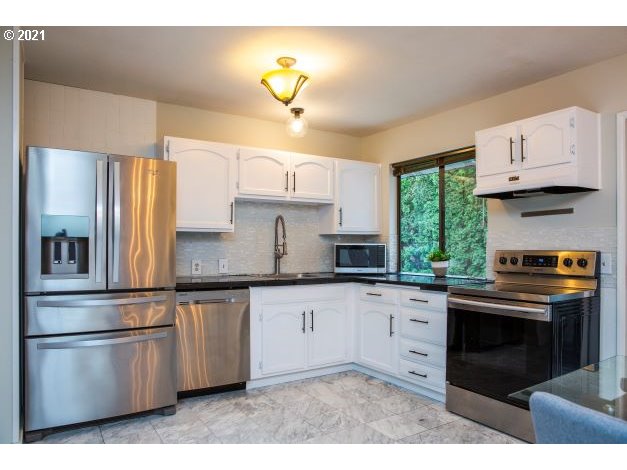 8325 Southwest Terwilliger Boulevard Portland, OR 97219 - Photo 7 of 30 a kitchen with stainless steel appliances granite countertop a stove a sink and a refrigerator