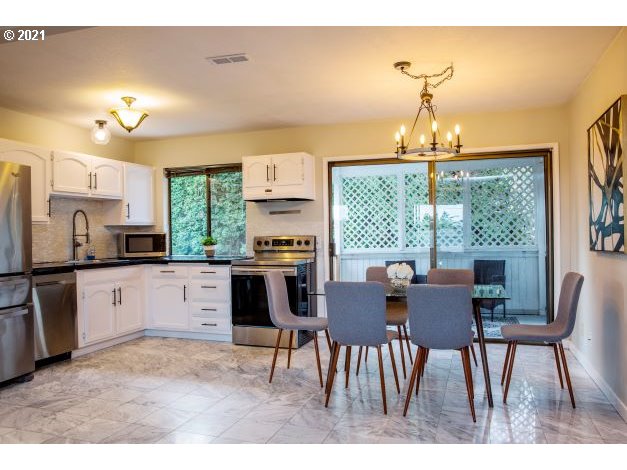8325 Southwest Terwilliger Boulevard Portland, OR 97219 - Photo 8 of 30 a open dining room with stainless steel appliances kitchen island granite countertop furniture and a chandelier