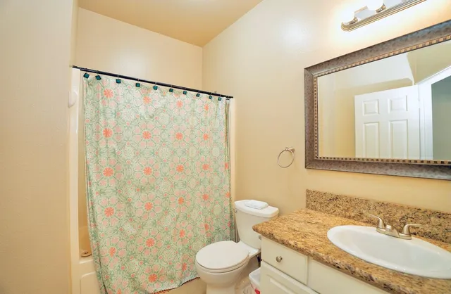 a bathroom with a granite countertop sink toilet and shower