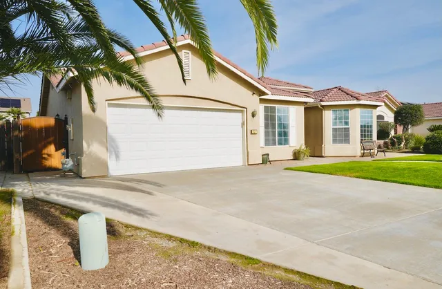 a view of a white house with a yard and potted plants