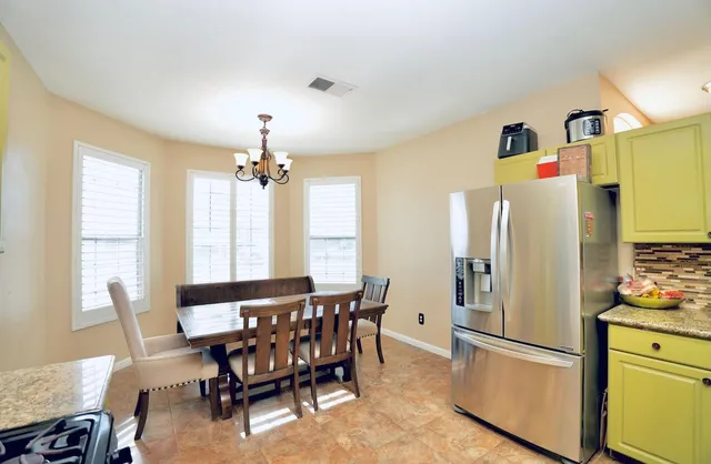 a kitchen with stainless steel appliances a dining table chairs refrigerator and sink