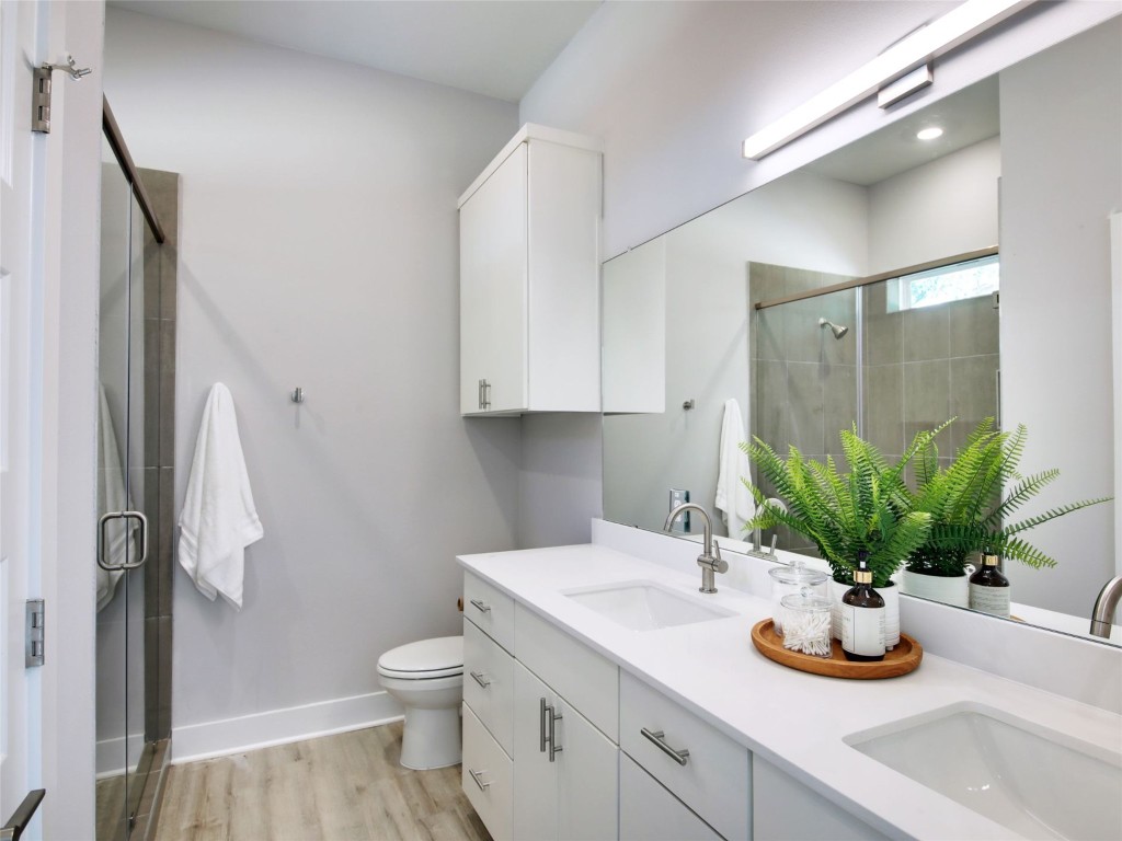 6111 Carnation Terrace, Unit 1 Austin, TX 78741 - Photo 16 of 23 a bathroom with a granite countertop sink a toilet and a mirror