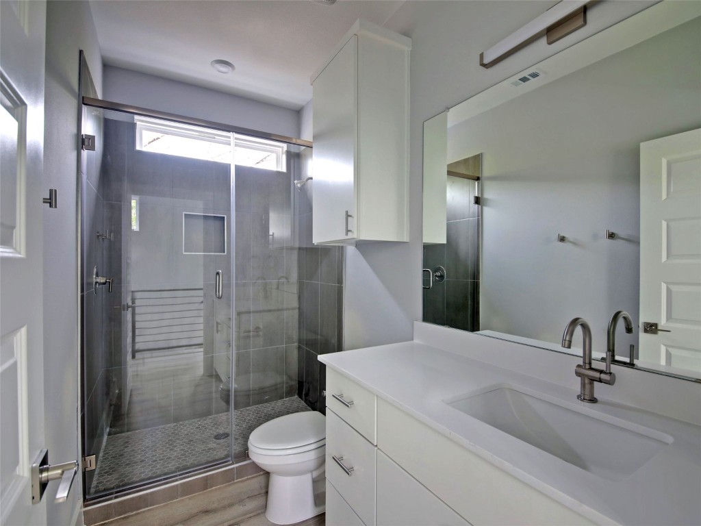 6111 Carnation Terrace, Unit 1 Austin, TX 78741 - Photo 20 of 23 a bathroom with a shower sink vanity mirror and toilet