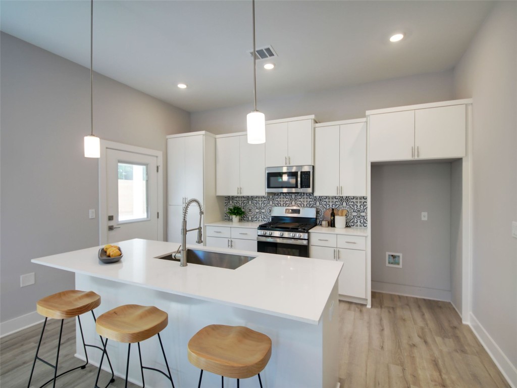 6111 Carnation Terrace, Unit 1 Austin, TX 78741 - Photo 5 of 23 a kitchen with stainless steel appliances a kitchen island hardwood floor sink stove dining table and chairs