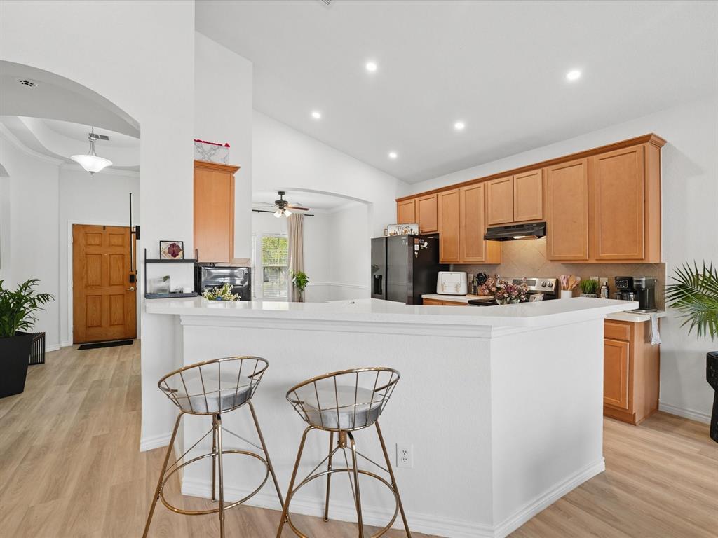 6527 Portside Ridge Lane Dallas, TX 75249 - Photo 16 of 30 a kitchen with stainless steel appliances granite countertop a refrigerator a stove a sink dishwasher and a dining table with wooden floor