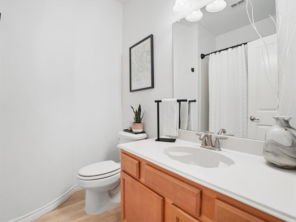 6527 Portside Ridge Lane Dallas, TX 75249 - Photo 26 of 30 a bathroom with a granite countertop sink a toilet and mirror
